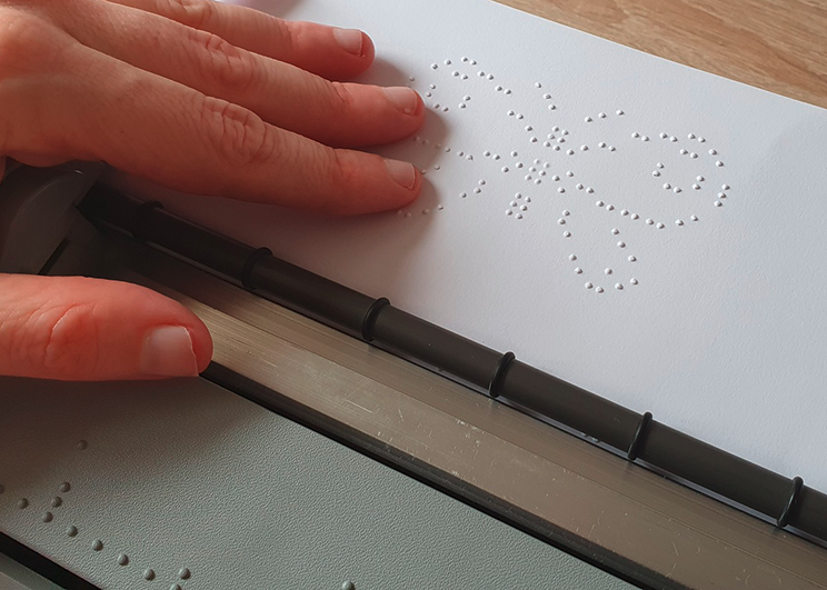 Nahaufnahme einer Hand, die ein Braillebild ertastet