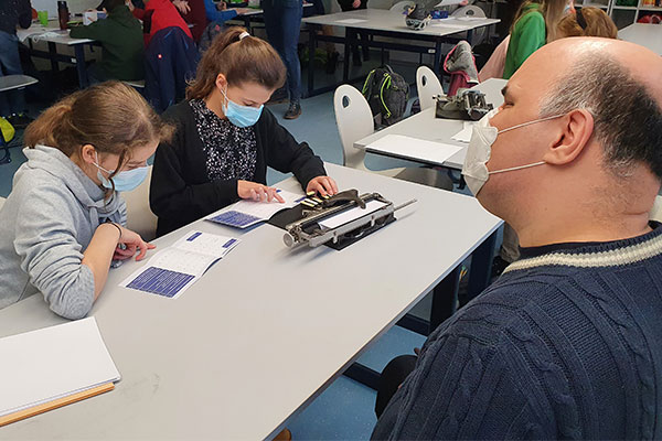 Zwei Schülerinnen probieren unter Anleitung eines Vereinsmitgliedes die Schreibmaschine für Blindenschrift aus.